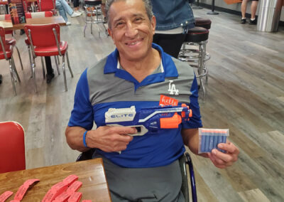 A man smiling while holding an Elite water gun.