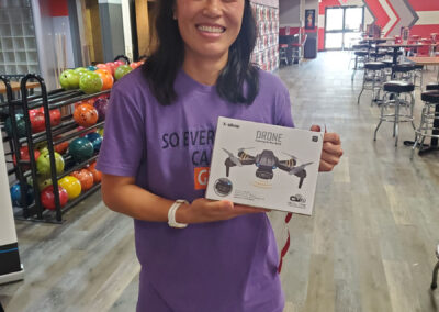 A woman smiling, holding a box with a drone inside.