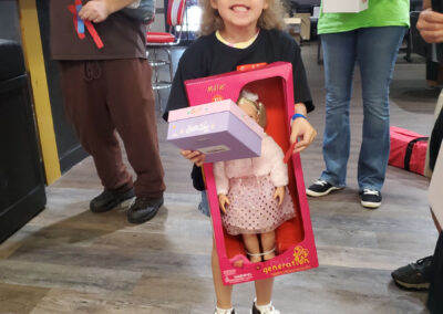 A little girl holding a doll in a box and a girl shoe box.