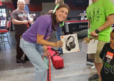 A woman holding a box of Bluetooth headphones, standing next to Eric of Vascular Surgical Atlanta.