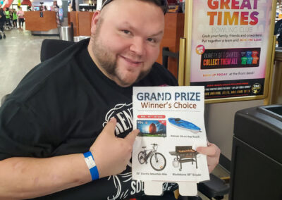 A man in a wheelchair holding an announcement about the Grand Prize Winner’s Choice.