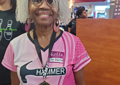 A lady smiling, wearing her Champion medal at Bowler Bash.