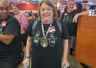 An older lady in a walker, smiling while wearing a Runner Up medal.