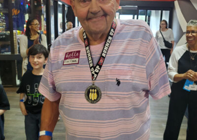 An older man wearing a Runner Up medal and smiling at the camera.