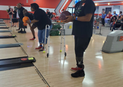 A shot of many physically handicapped people about to throw bowling balls.