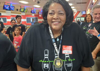 A lovely lady smiling, wearing a Champion medal and a Amputee Bowler Bash t-shirt.