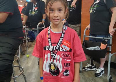 A young girl supporting the Bowler Bash with a t-shirt and a medal.