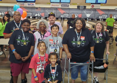 A group of physically handicapped people smiling with kids and others.