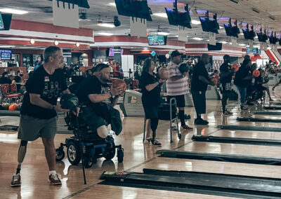 A group of people wearing prosthetics holding bowling balls in front of their lanes.