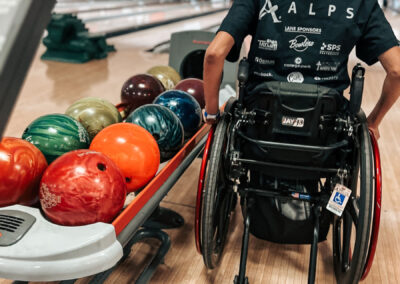 A woman in a wheelchair looking at bowling balls.