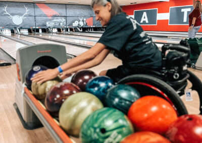 A woman in a wheelchair picking out her bowling ball.