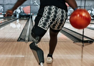 A man with a prosthetic leg throwing a bowling ball in action.