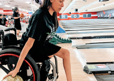 A woman with a missing leg and in a wheelchair bowling.