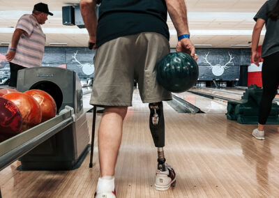 A man with a prosthetic leg holding a bowling ball, about to make his move.