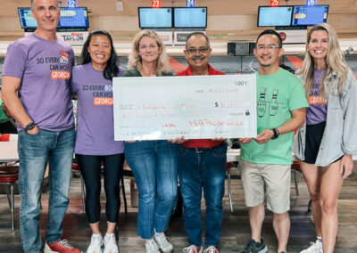 A group of people smiling at Bowlero, holding an oversized check of $10,000 for So Everybody Can Move Georgia.